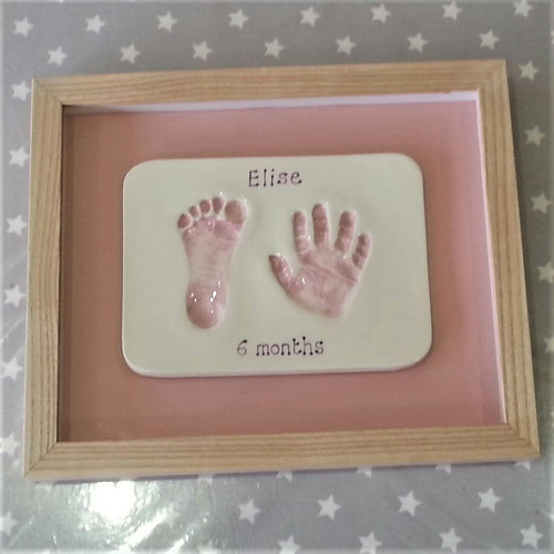 Rectangle Clay Imprint with foot and hand print in pink with pink back board and wooden frame.