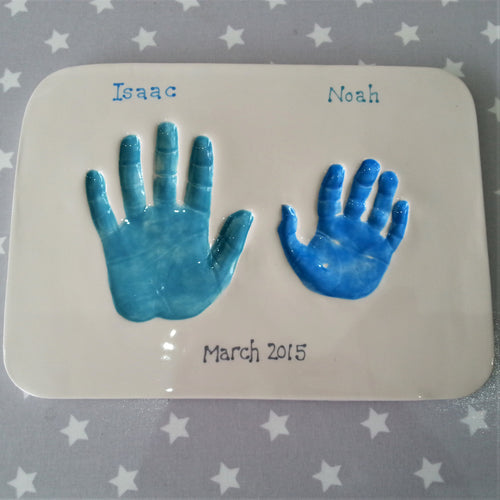 Rectangle Clay Imprint with sibling hand prints. Larger print in teal and smaller print in blue.  Unframed.