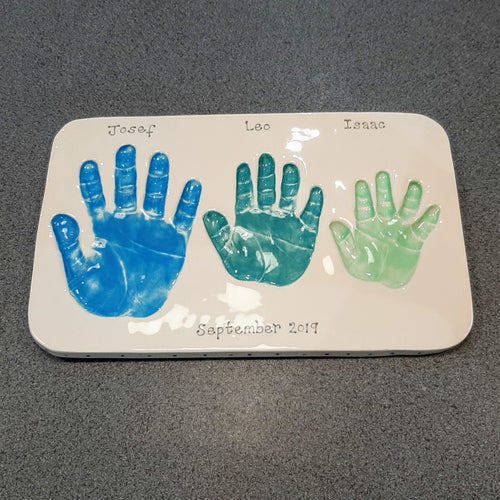 Rectangle Clay Imprint with three sibling hand prints in blue, teal and mint green.  Unframed.