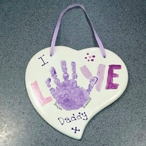 A Curved Heart Plaque with purple hand print making the letter O in the word LOVE.