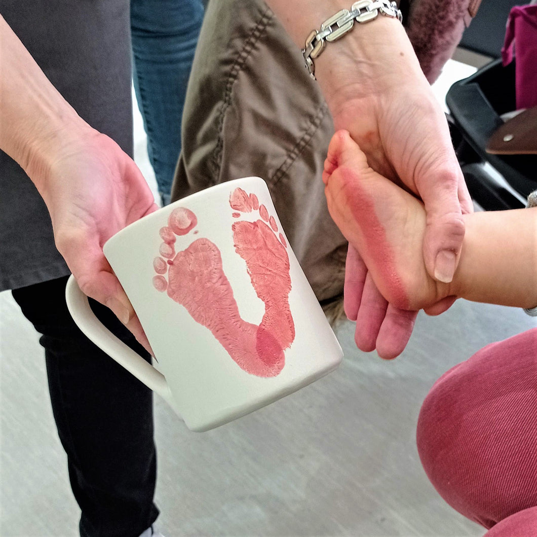 Taking baby footprints on a mug at Create It.  These red footprints will become the letter V in the word LOVE.