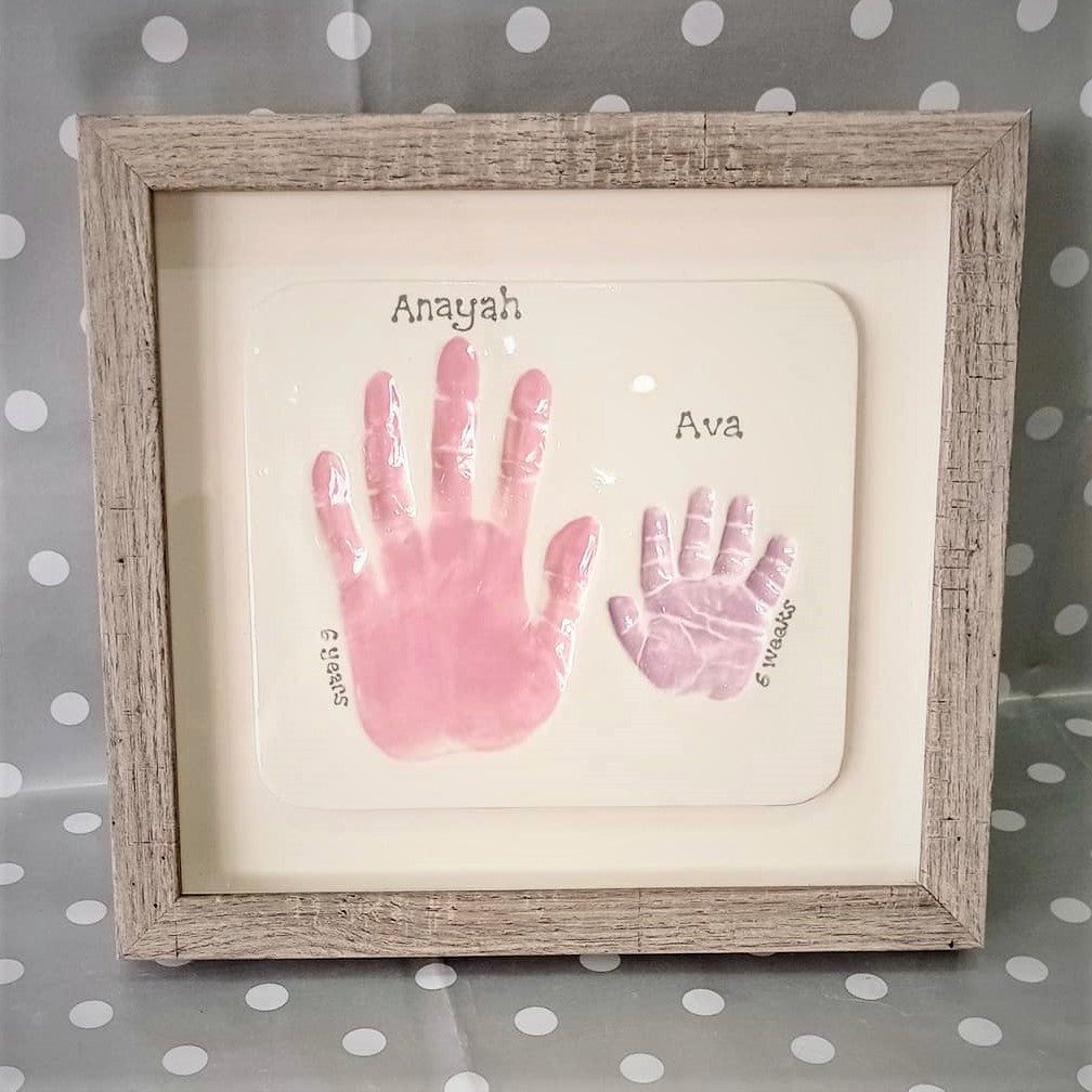 Clay Imprint framed with two hand prints in pink and purple.