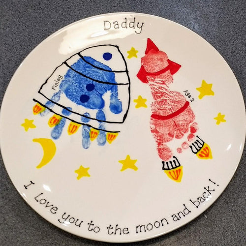 Medium Coupe Plate with blue hand print turned into a space ship and a red footprint turned into a space rocket. 