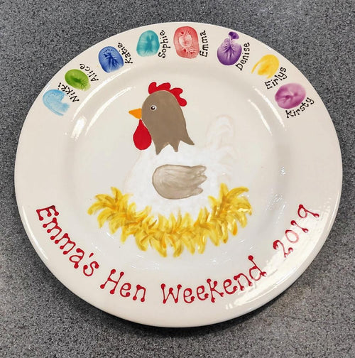 A hen weekend keepsake plate, made at a Hen Party at Create It, with painted finger prints of the guests and a painted hen in the centre. 