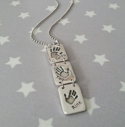 Love Prints hand print necklace.  Sterling silver necklace with 3 connected medium rectangle charms with a hand print in each.