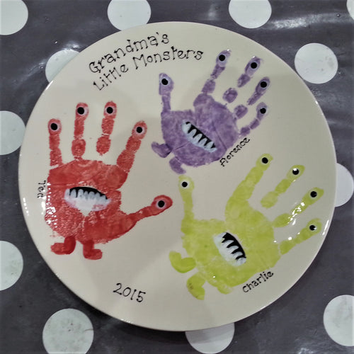 Large Coupe Plate with three siblings hand prints in red, purple and green, turned into monsters, as a gift for Grandma.