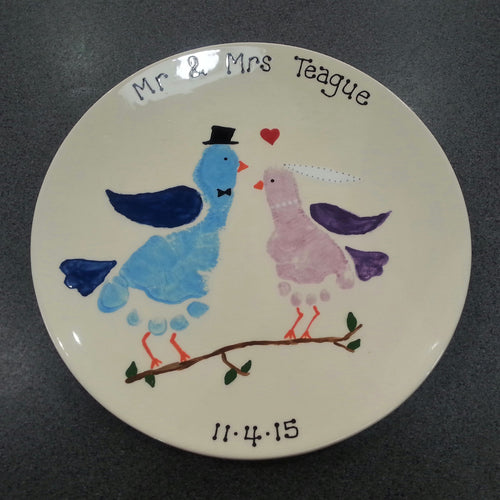 Large Coupe Plate with blue footprint turned into a bird as a groom, and a smaller sibling footprint in purple, turned into a bird as a bride, as a wedding gift. 