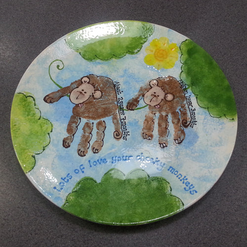 Large Coupe Plate decorated with sky and tree detail and two brown hand prints turned into monkeys as a gift 'from your cheeky monkeys'.