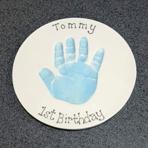 Round Clay Imprint with a hand print in pastel blue. Unframed.