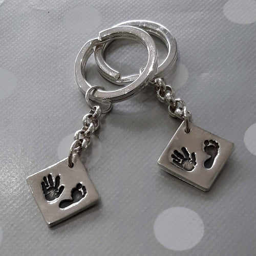 Love Prints medium square charms set as diamond shape with hand and foot prints on each, attached to sterling silver key chains and keyrings.