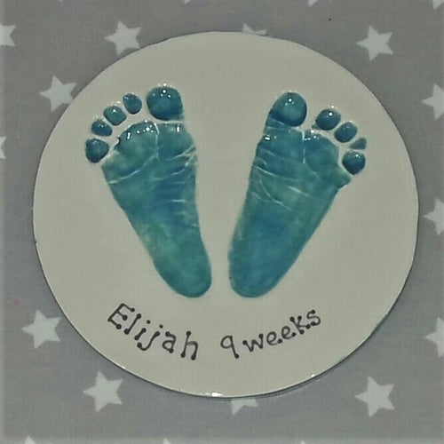 Circle Clay Imprint with two footprints in teal.  Unframed. 