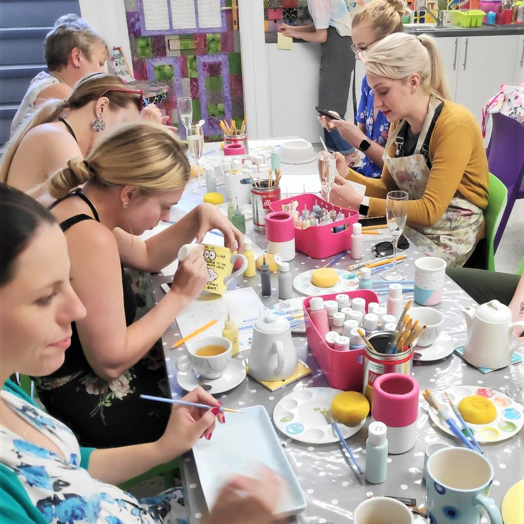 A group of adult pottery painters enjoying a creative evening.