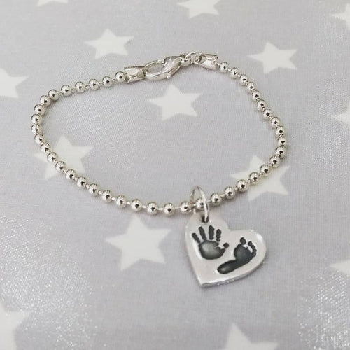 Love Prints heart charm with hand and foot print on silver bead chain bracelet.