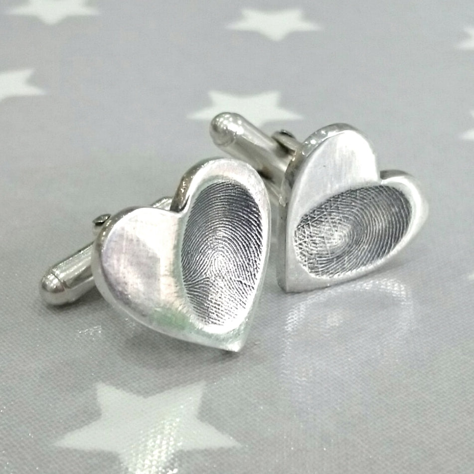 A pair of heart shaped Love Prints silver imprint cufflinks with a fingerprint in each cufflink.