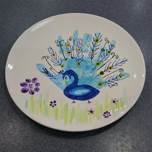 Small Coupe Plate with blue hand print turned into a peacock, with grass detail. 