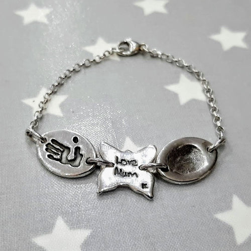 Love Prints bracelet with two medium oval charms with a fingerprint and hand print with a butterfly charm inbetween with hand writing on. 