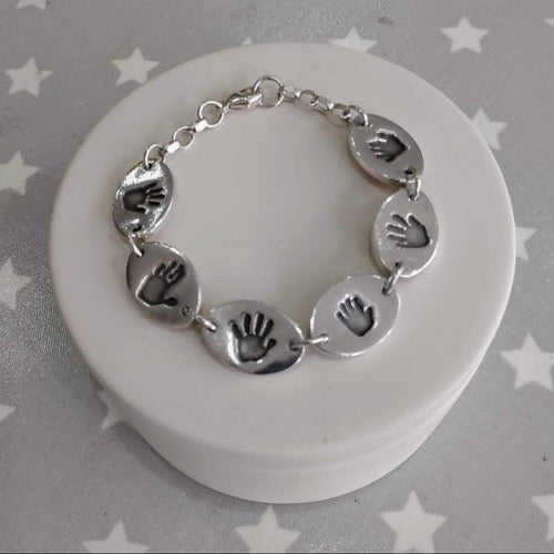 Love Prints hand print bracelet.  6 connected medium oval charms with a hand print on each with sterling silver bracelet connection.