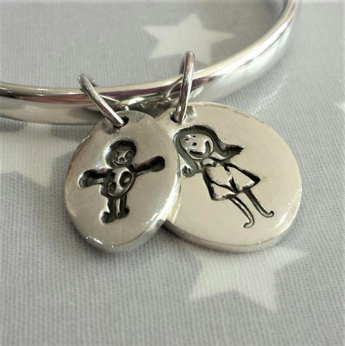 Love Prints large and medium oval charms with child's drawings on sterling silver bangle.